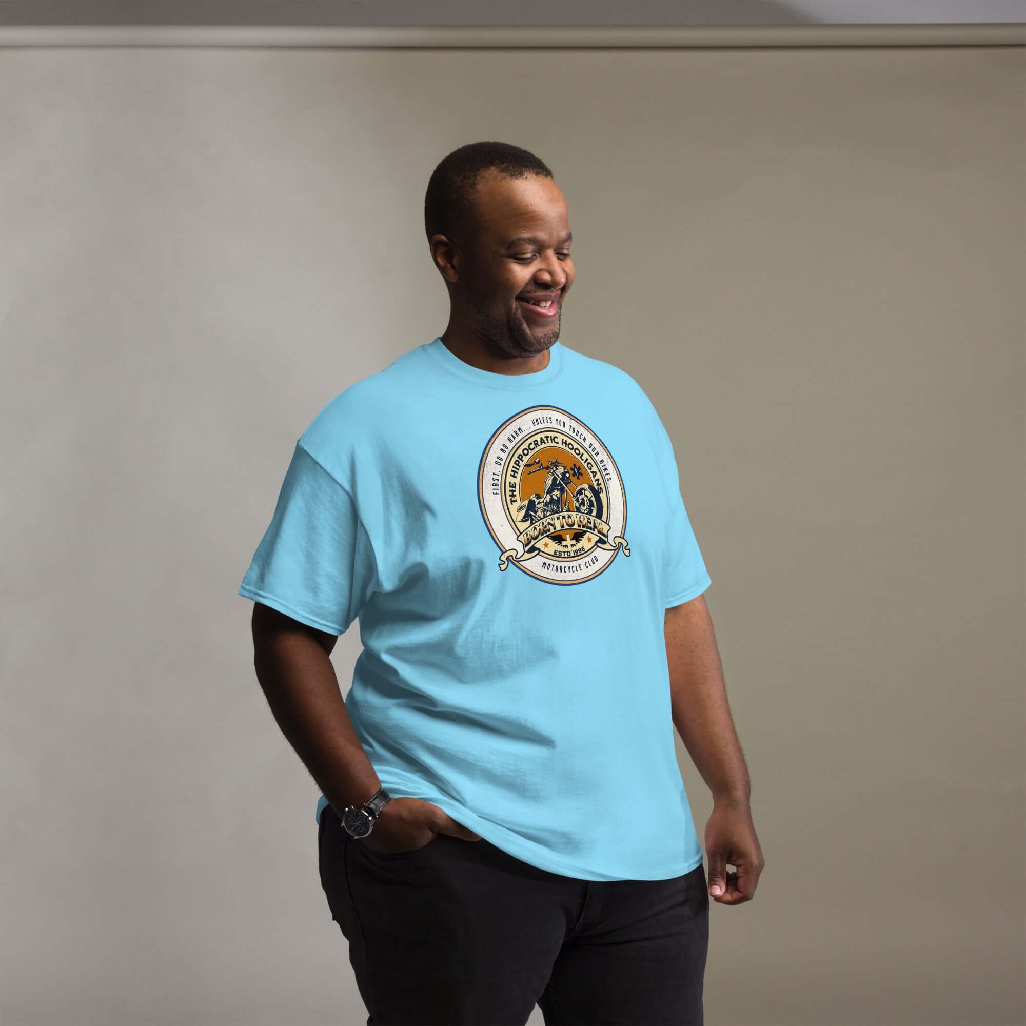 Man wearing a Hippocratic Hooligans Motorcycle Club T-Shirt with biker patch design, combining medicine and motorcycling themes.