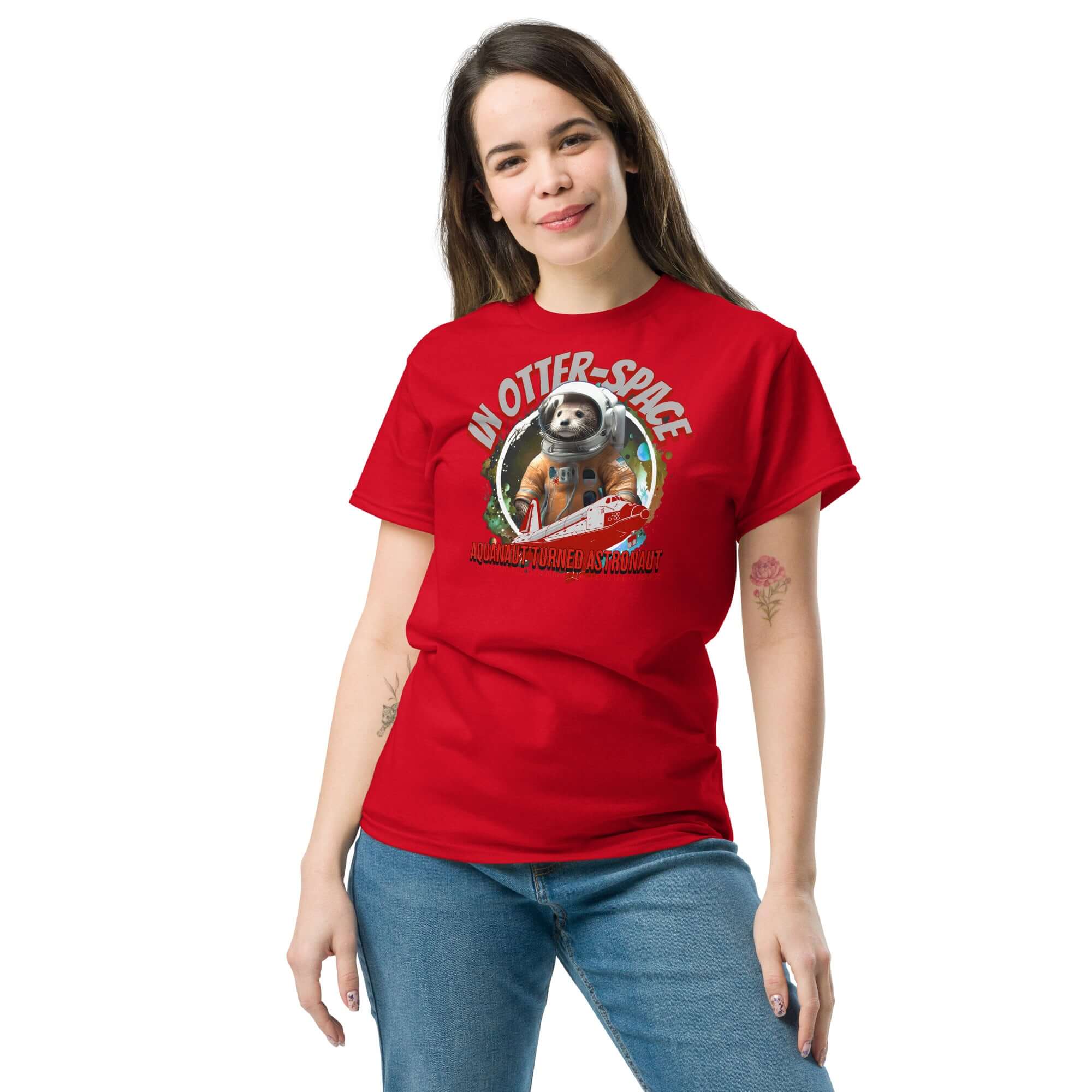 Red t-shirt featuring a cosmic otter in astronaut suit, "In Otter Space: Aquanaut Turned Astronaut" design, woman wearing jeans.