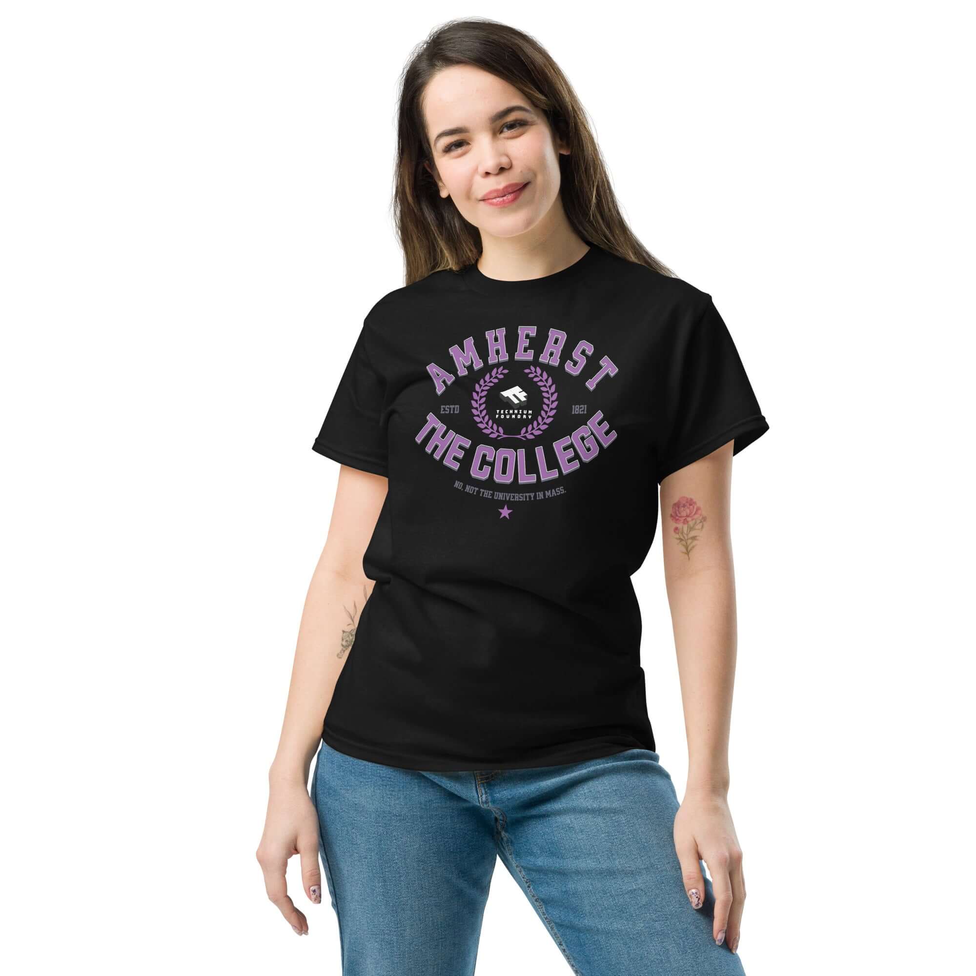Woman wearing Amherst Clarification T-Shirt with "Amherst: THE COLLEGE" text, black tee, humor, college identity theme.