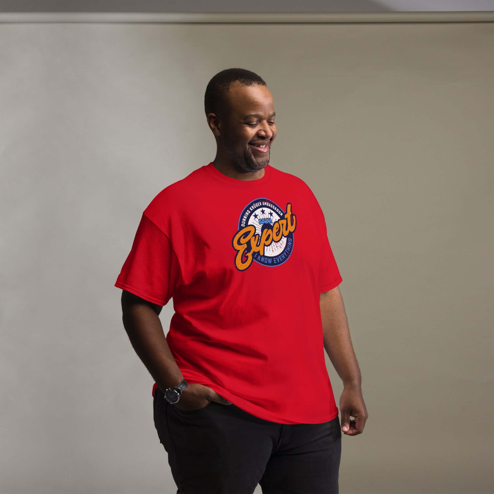 Man wearing red 'Dunning-Kruger Expert' t-shirt with circular emblem, combining humor and psychology in fashion.