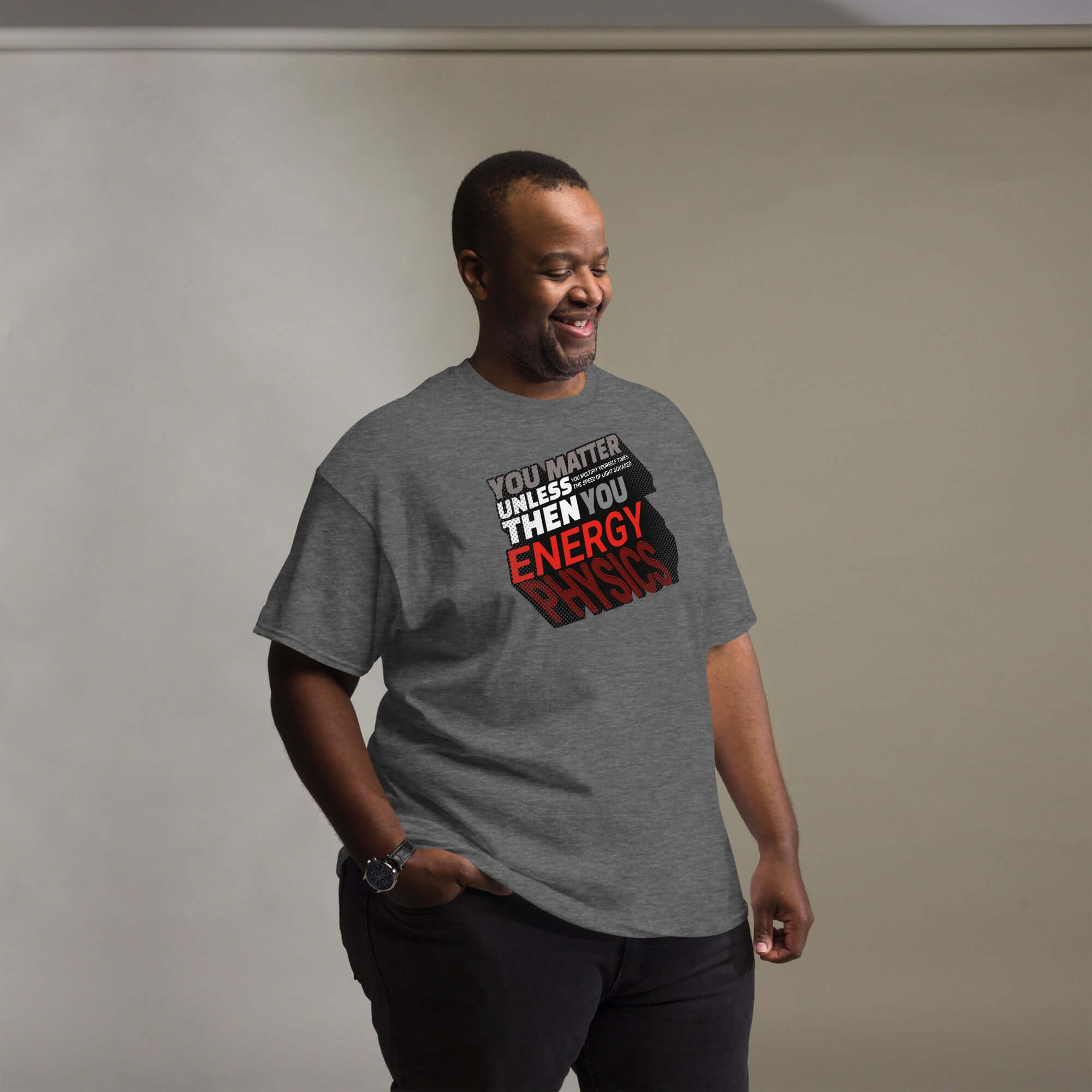 Man wearing gray T-shirt with E=mc² transformed into a humorous physics sentence, emphasizing 'Energy' in red text, standing and smiling.