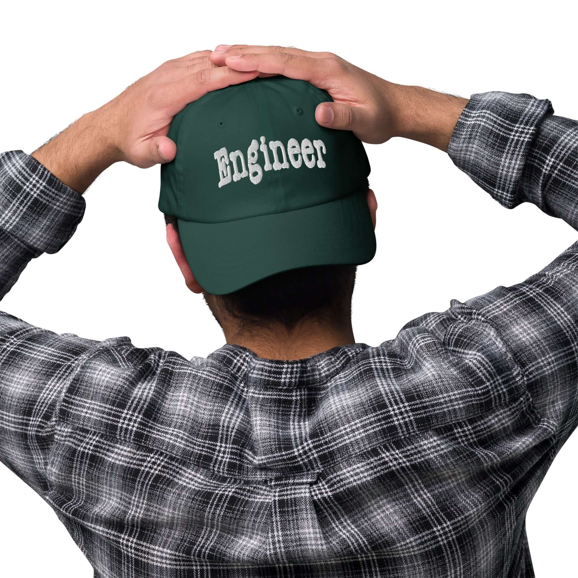Back view of person wearing green "Engineer" baseball cap, hands on head, flannel shirt. Problem-solving headwear with style.