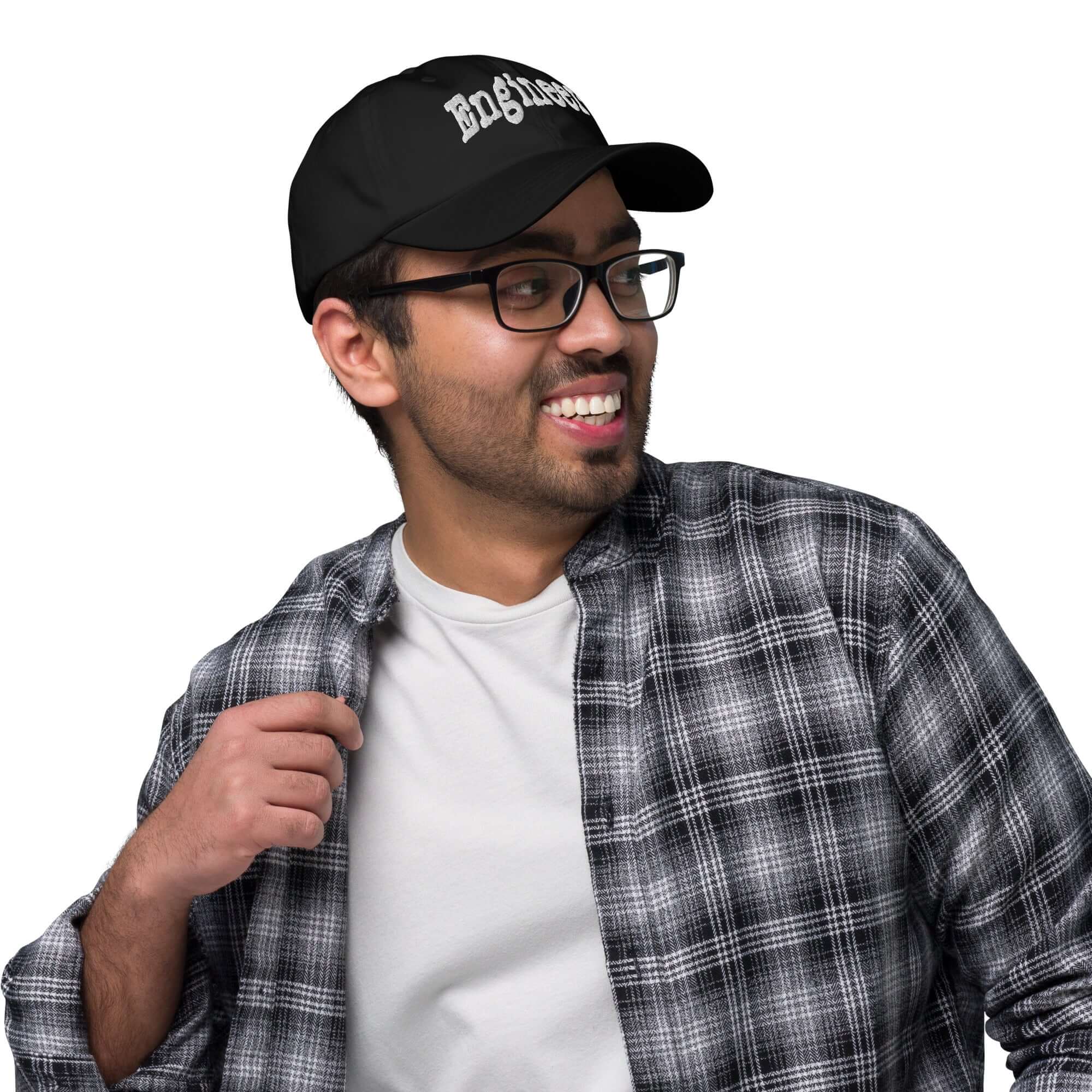 Man smiling in plaid shirt wearing "ENGINEER" baseball cap, exuding problem-solving professionalism and style.