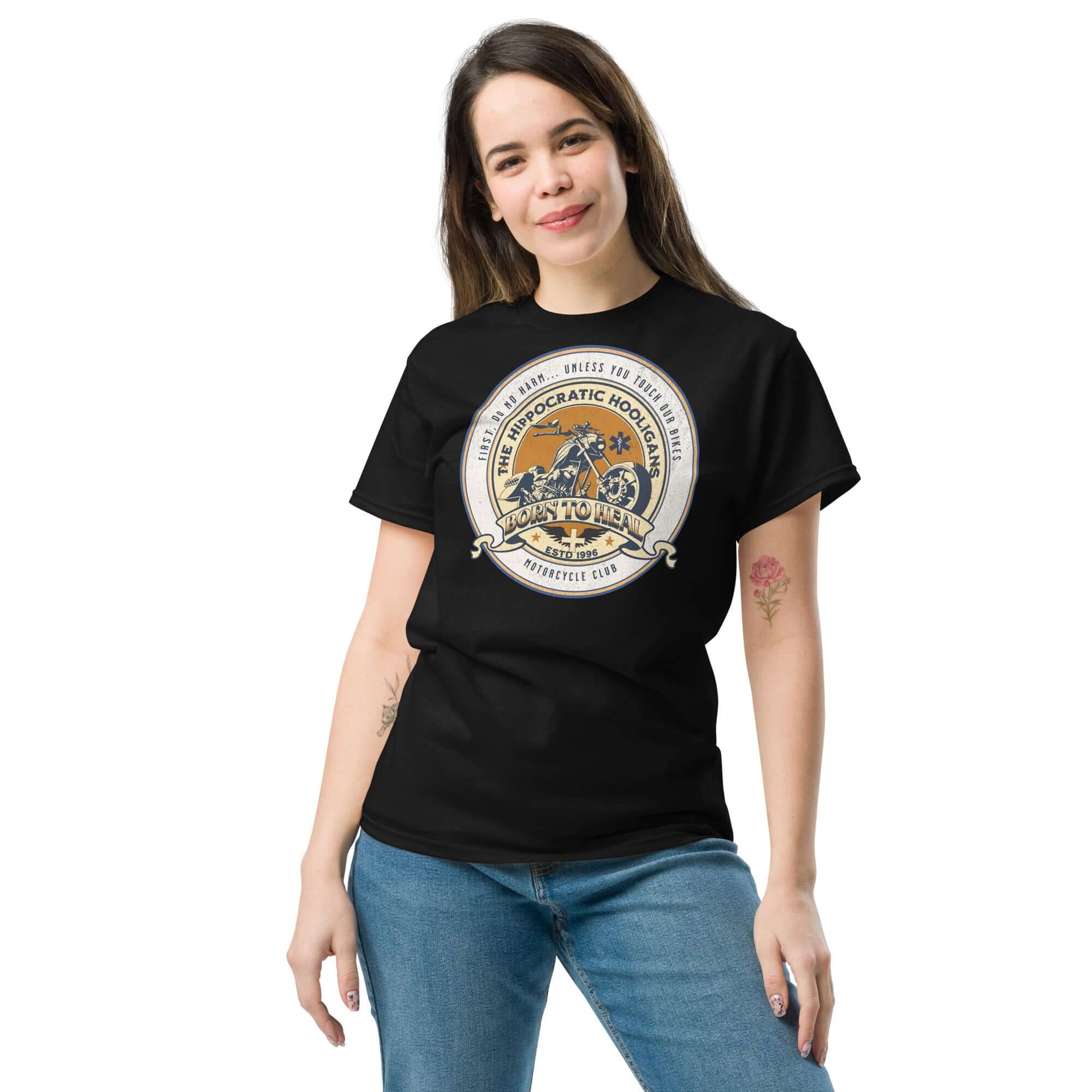 Woman wearing Hippocratic Hooligans Motorcycle Club T-Shirt, featuring biker patch design celebrating medicine and motorcycle culture.