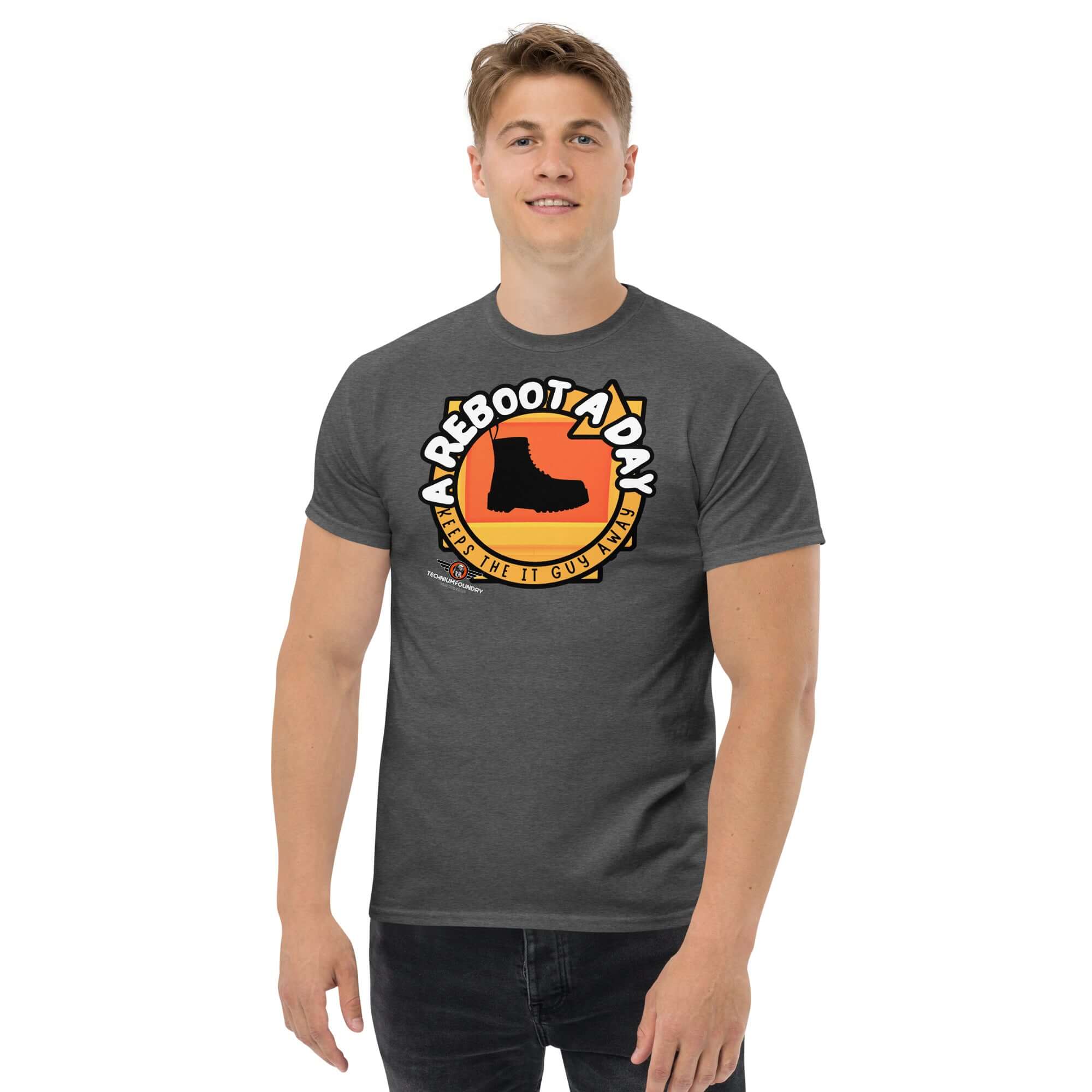 "A Reboot A Day" IT support humor T-shirt with boot design, worn by a smiling man in a sunset-colored backdrop style.