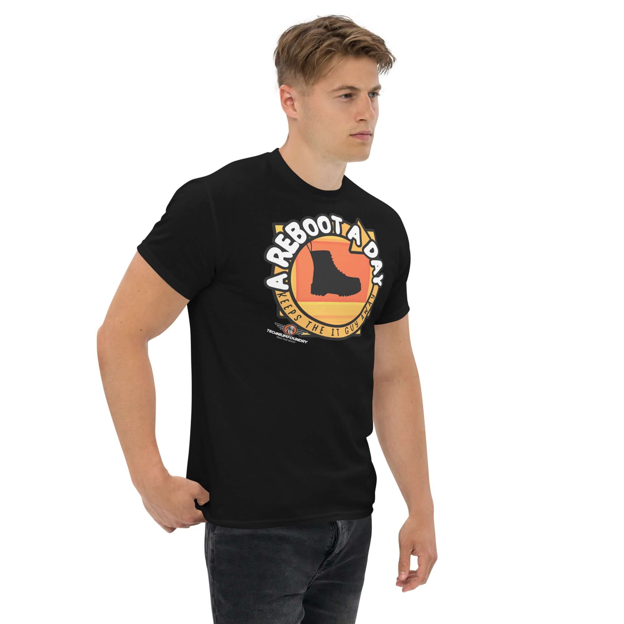 Man wearing black "A Reboot A Day" IT support humor t-shirt with combat boot design on tech help desk theme.