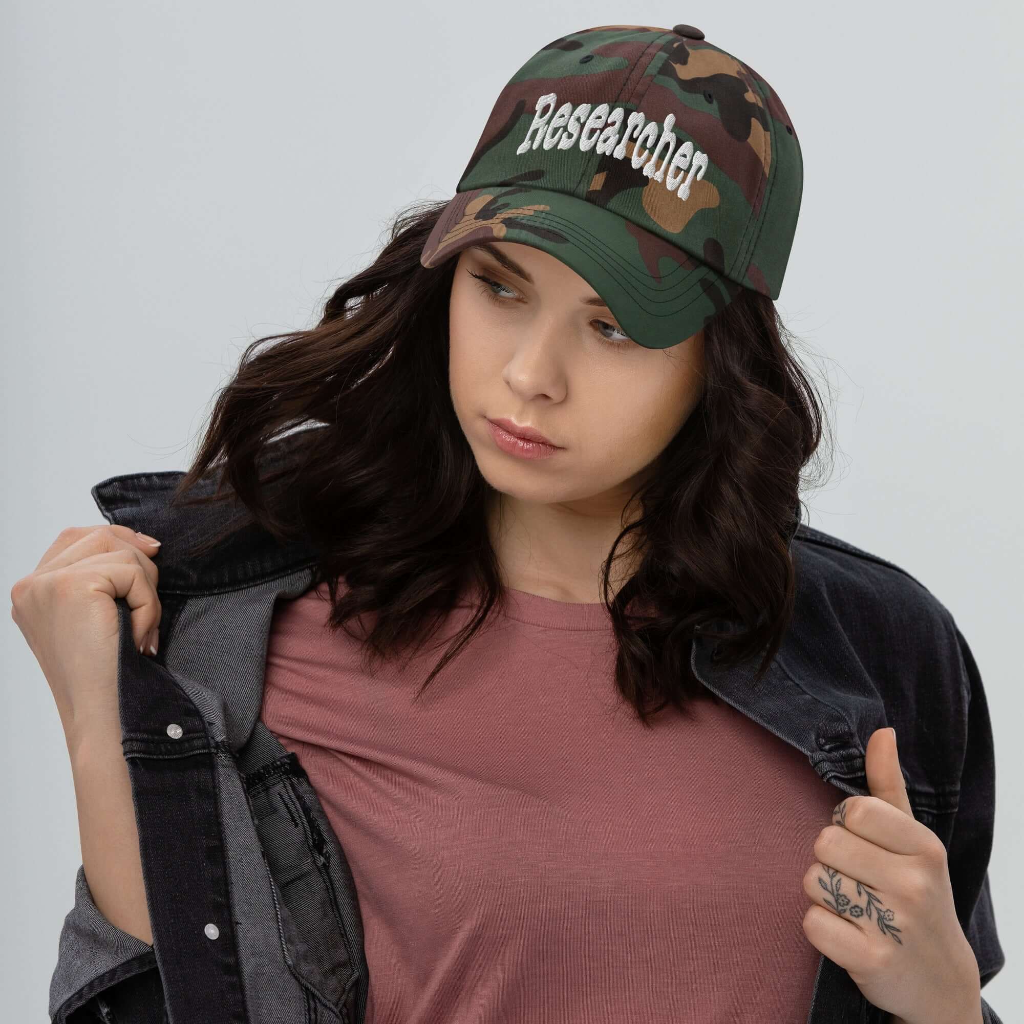 Woman wearing a camo "Researcher" baseball cap, showcasing professional question-asking headwear, ideal for curious minds.
