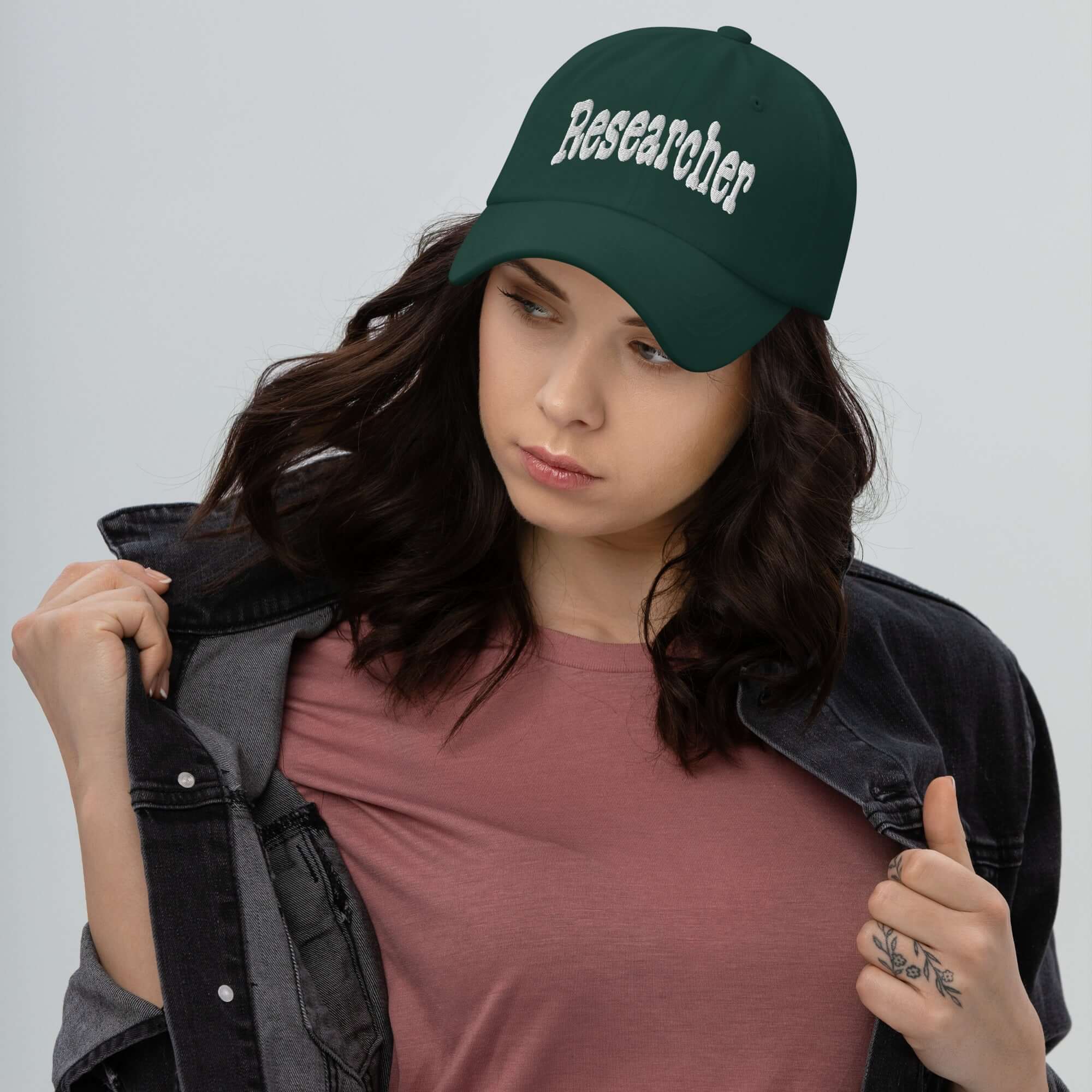 Woman wearing green 'Researcher' baseball cap, signifying professional question-asking and curiosity. Ideal for research enthusiasts.