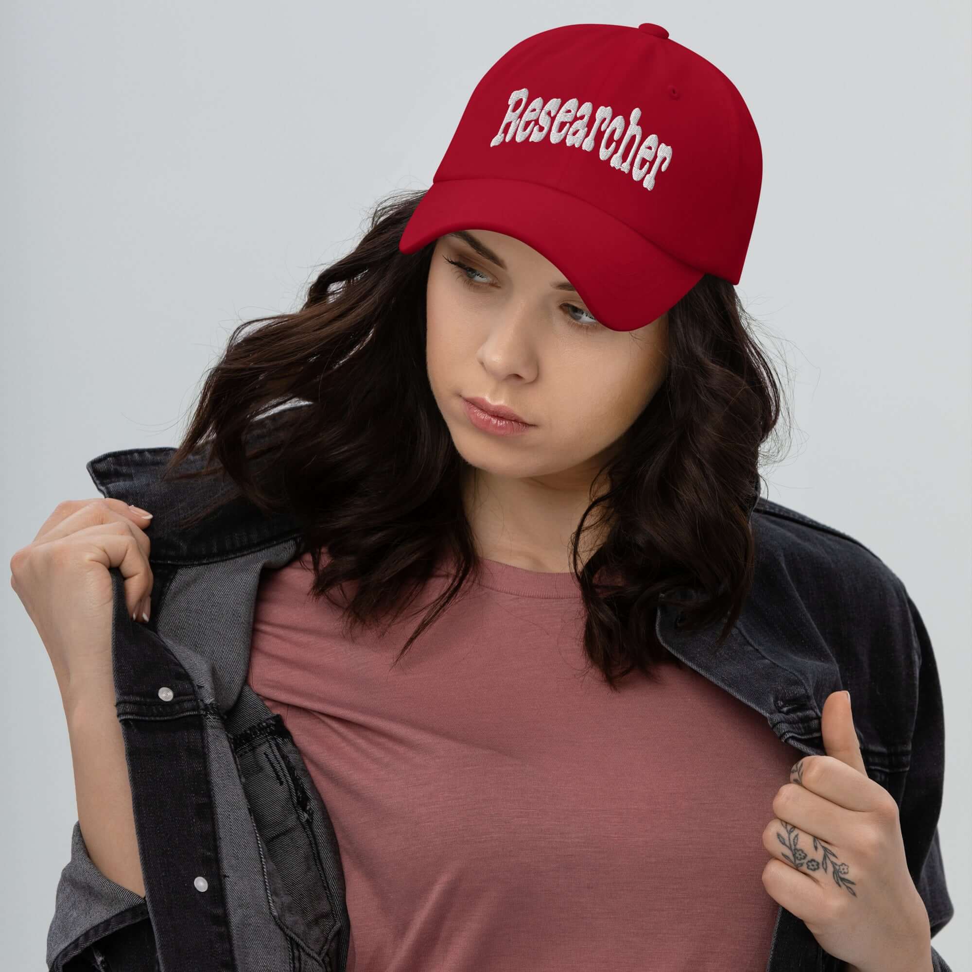 Woman wearing a red "Researcher" baseball cap, showcasing professional headwear ideal for those in the research field.