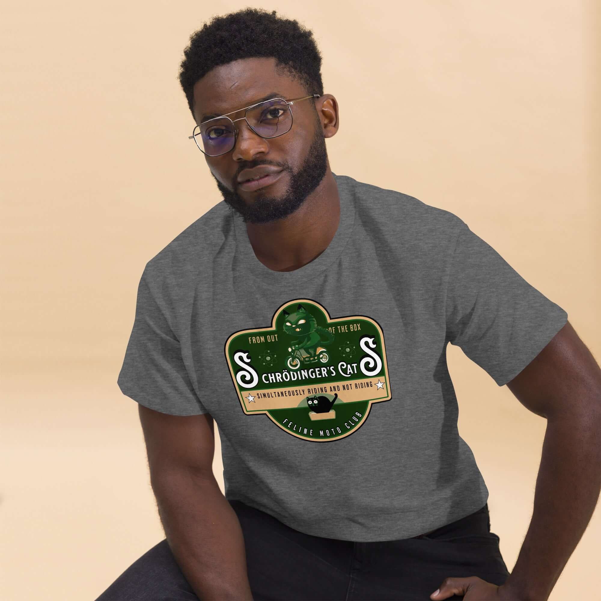 Man wearing Schrödinger's Cats Motorcycle Club T-Shirt featuring a cat emblem on a motorcycle, quantum physics theme, gray tee.